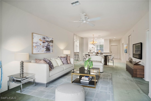 carpeted living room featuring ceiling fan with notable chandelier