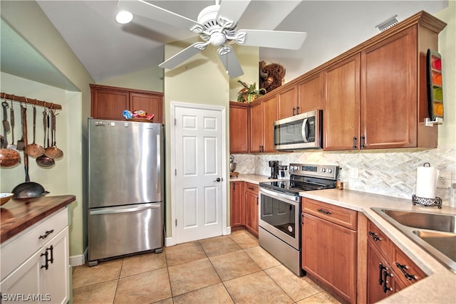 kitchen with appliances with stainless steel finishes, tasteful backsplash, light tile patterned floors, lofted ceiling, and ceiling fan