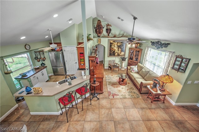 tiled living room with high vaulted ceiling, sink, and ceiling fan