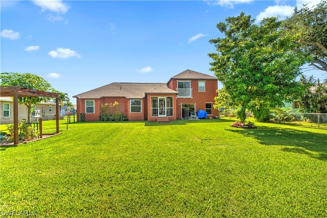 rear view of house featuring a pergola and a lawn