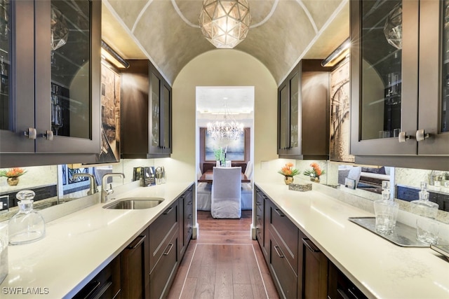 kitchen featuring a chandelier, sink, dark hardwood / wood-style floors, pendant lighting, and dark brown cabinetry