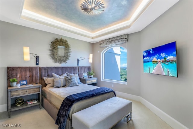 bedroom featuring a tray ceiling and light carpet