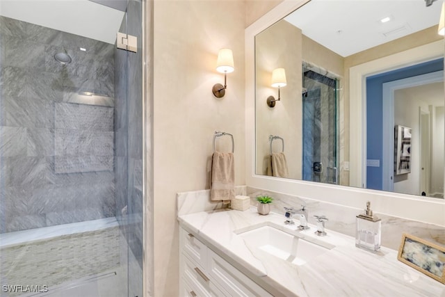 bathroom with a tile shower and vanity