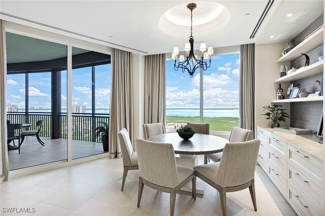 dining space featuring a healthy amount of sunlight, a notable chandelier, and a water view