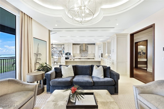 living room featuring light wood-type flooring, a tray ceiling, and an inviting chandelier