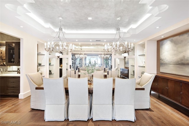 dining area featuring built in features, a notable chandelier, wood-type flooring, and a tray ceiling