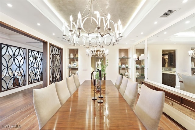 dining area with light wood-type flooring, a raised ceiling, and a chandelier