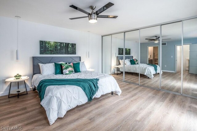 bedroom featuring baseboards, visible vents, a ceiling fan, and wood finished floors