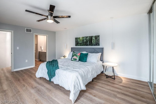 bedroom featuring visible vents, baseboards, wood finished floors, and ensuite bathroom