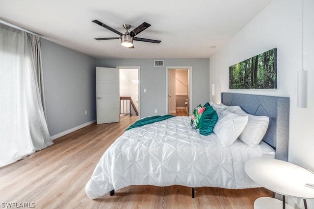 bedroom featuring light wood finished floors, a ceiling fan, visible vents, and baseboards