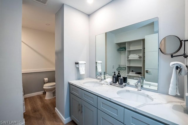 bathroom with double vanity, baseboards, a sink, and wood finished floors