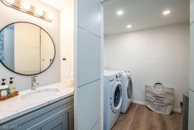 laundry room with a sink, wood finished floors, washing machine and clothes dryer, and recessed lighting