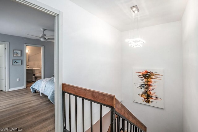 hall with baseboards, dark wood-style flooring, and an upstairs landing