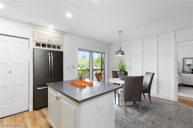 kitchen with stainless steel fridge, white cabinetry, a center island, decorative light fixtures, and light wood-type flooring