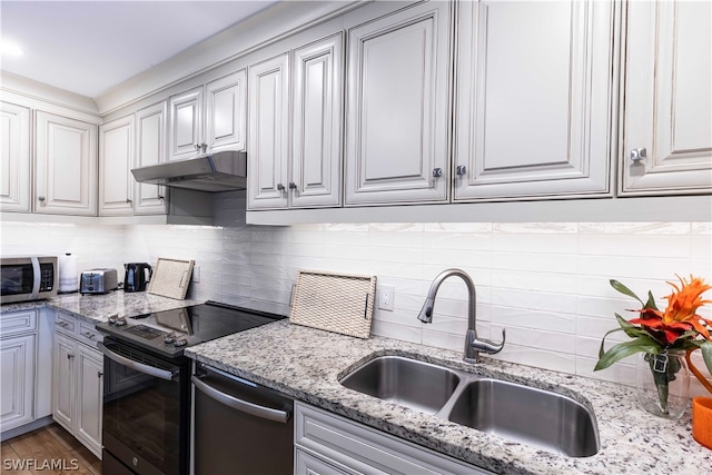 kitchen with sink, stainless steel appliances, tasteful backsplash, light stone countertops, and dark hardwood / wood-style flooring