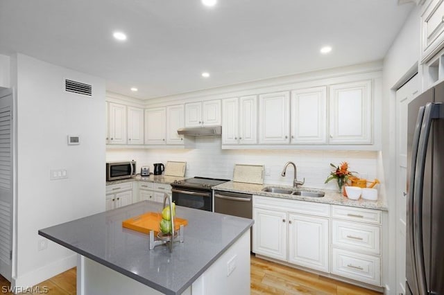 kitchen featuring sink, white cabinetry, stainless steel appliances, light hardwood / wood-style floors, and a kitchen island