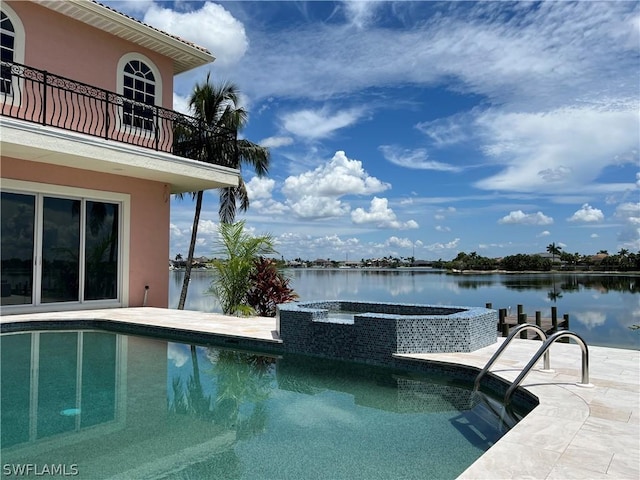 view of pool with an in ground hot tub, a water view, and a patio area