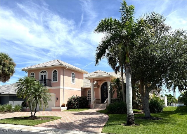 mediterranean / spanish home with a garage and a front lawn