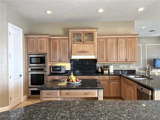 kitchen with stainless steel appliances, tasteful backsplash, sink, and dark stone countertops