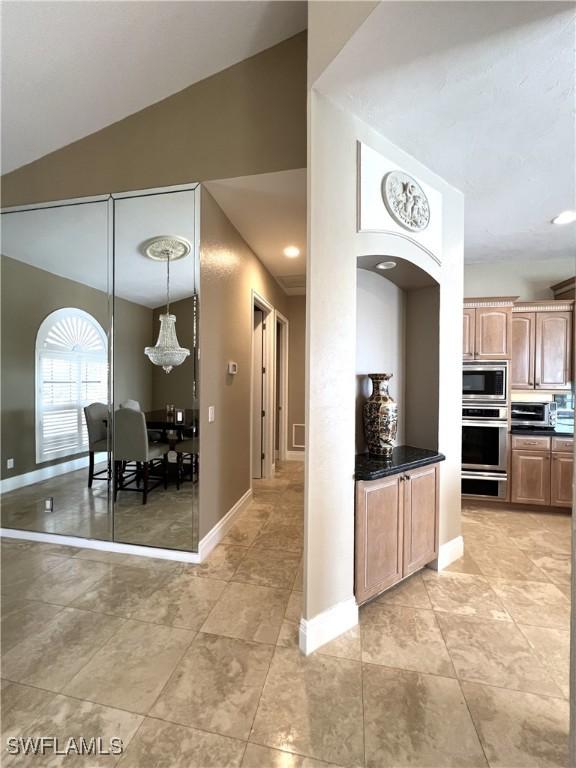 kitchen with hanging light fixtures, vaulted ceiling, and stainless steel appliances