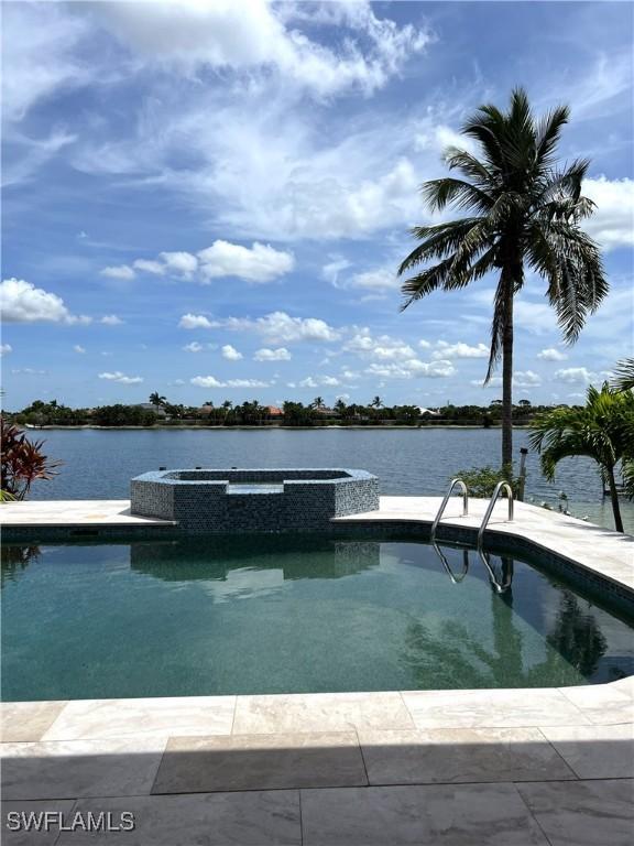 view of pool featuring an in ground hot tub and a water view