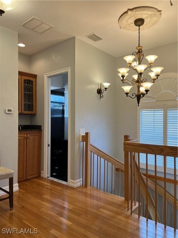 hall with an inviting chandelier and wood-type flooring