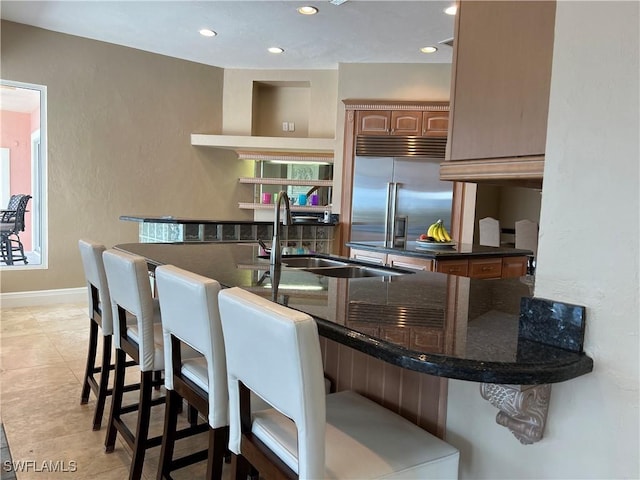 kitchen featuring a kitchen breakfast bar, stainless steel built in fridge, sink, and kitchen peninsula