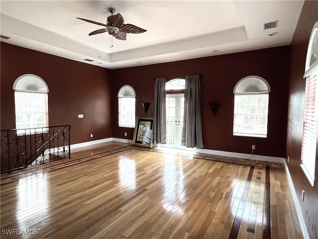 unfurnished room featuring ceiling fan, wood-type flooring, and a raised ceiling