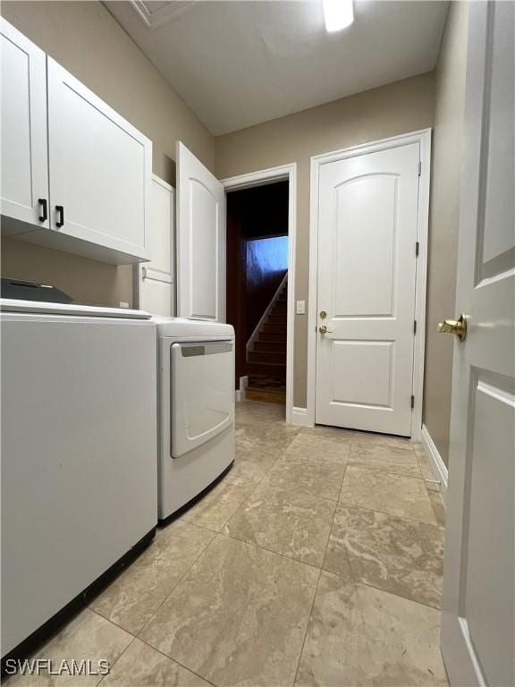 washroom with cabinets and washing machine and clothes dryer