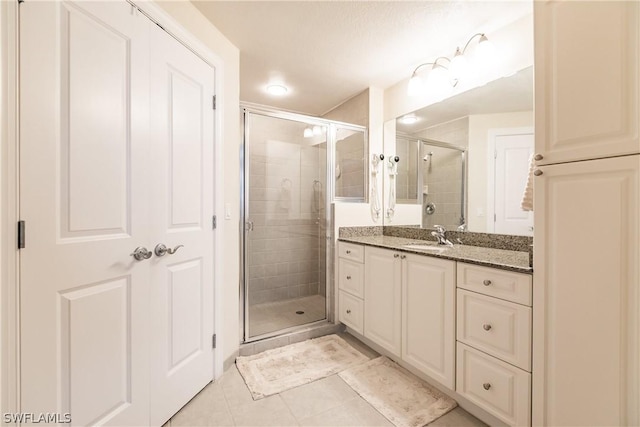 bathroom featuring a shower with door, vanity, and tile patterned flooring