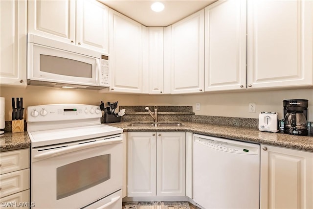 kitchen featuring white appliances, dark stone counters, sink, and white cabinets