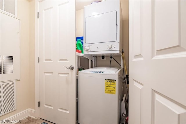 laundry area with light tile patterned flooring and stacked washer / dryer