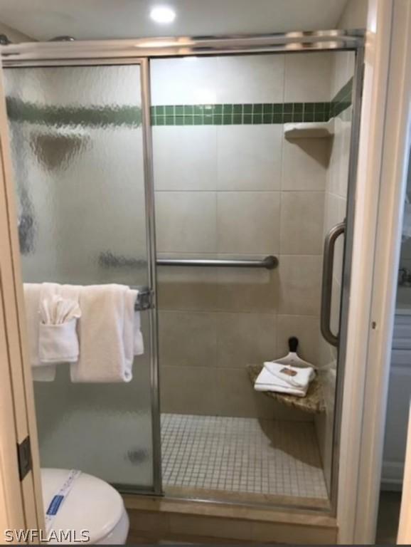 bathroom with a shower with door and toilet