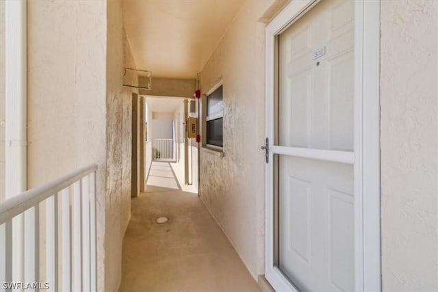 corridor with a textured wall and unfinished concrete floors