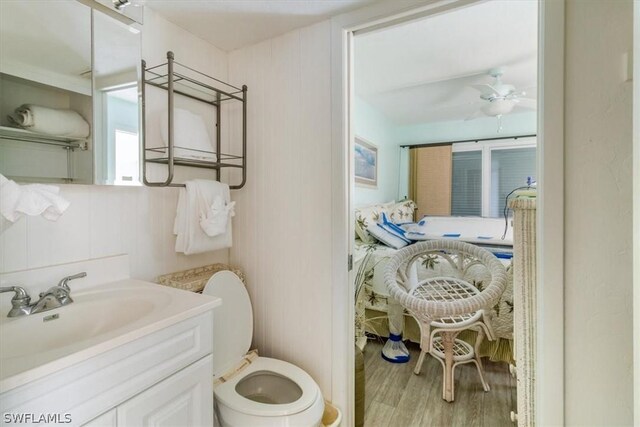 bathroom featuring hardwood / wood-style flooring, toilet, vanity, and ceiling fan