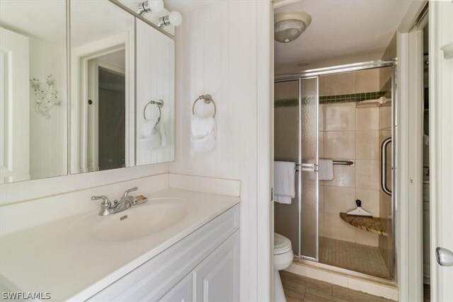 bathroom with a shower with door, toilet, and vanity