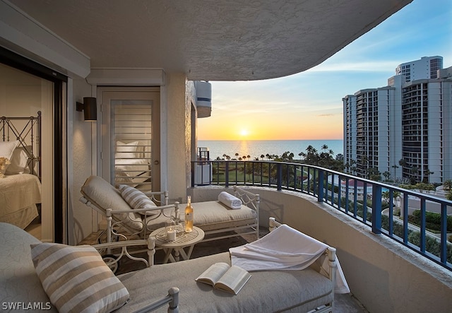 balcony at dusk featuring a water view