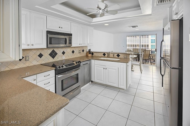 kitchen with a raised ceiling, sink, white cabinets, kitchen peninsula, and stainless steel appliances