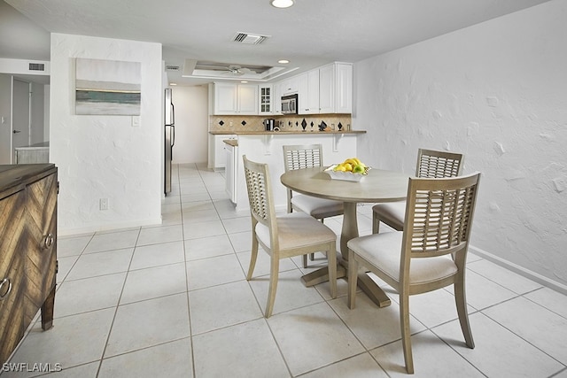 tiled dining space with a raised ceiling