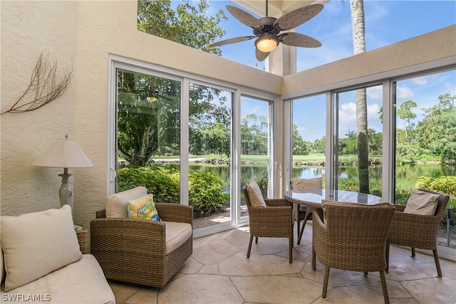 sunroom / solarium featuring a water view and ceiling fan