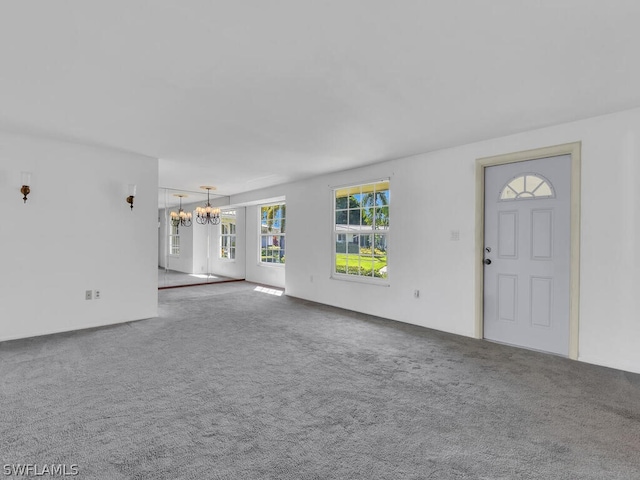 unfurnished living room with an inviting chandelier and carpet floors