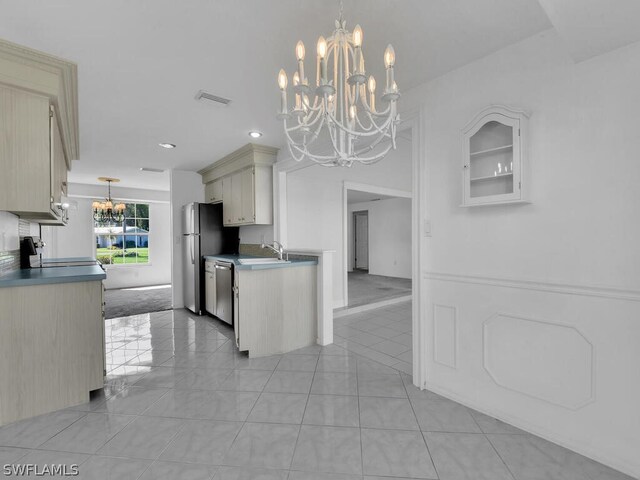 kitchen with appliances with stainless steel finishes, pendant lighting, a notable chandelier, sink, and light colored carpet