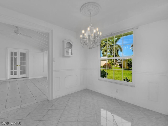empty room featuring ceiling fan with notable chandelier, vaulted ceiling, light tile patterned floors, and french doors