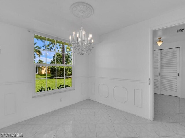 tiled spare room featuring a chandelier