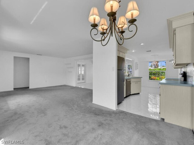 unfurnished living room featuring light carpet, a notable chandelier, and a sink