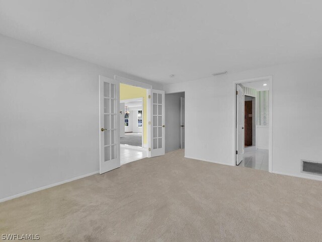 carpeted spare room featuring french doors