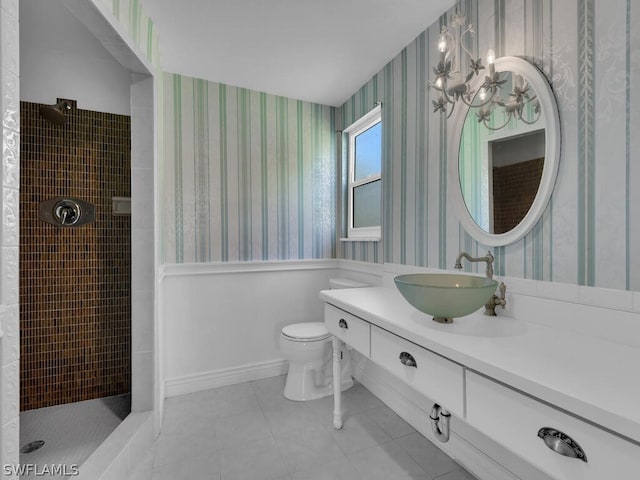 bathroom with toilet, a tile shower, vanity, and tile patterned floors