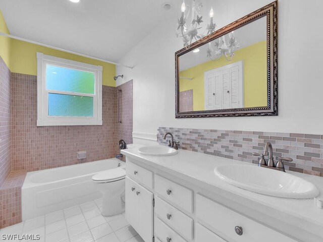 full bathroom with double sink vanity, toilet, tile patterned floors, and tiled shower / bath combo