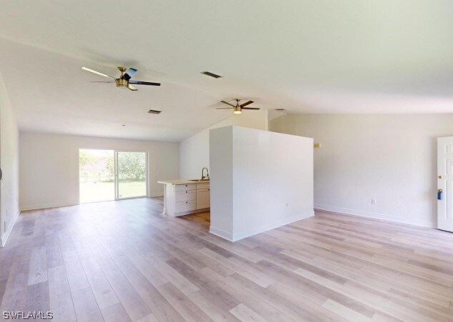 unfurnished living room with light hardwood / wood-style floors, sink, and ceiling fan