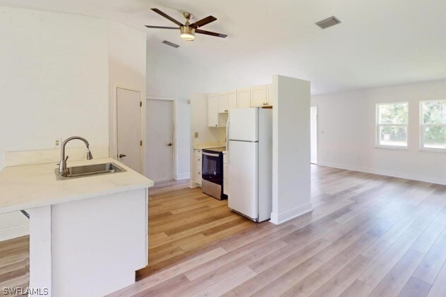 kitchen with white fridge, light hardwood / wood-style floors, sink, and kitchen peninsula